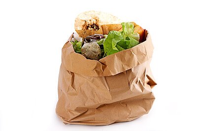 Kommunale Abfallwirtschaft Papiertüte mit richtig sortierten Bioabfällen wie Salatresten, Kartoffelschalen, Kaffeefilter